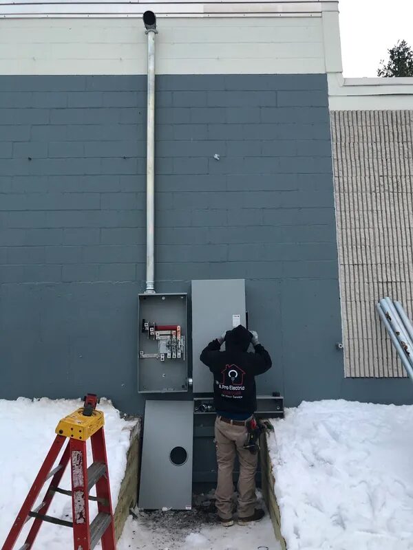 A. Pro Electric technician working inside an open disconnect on a commercial wall in winter